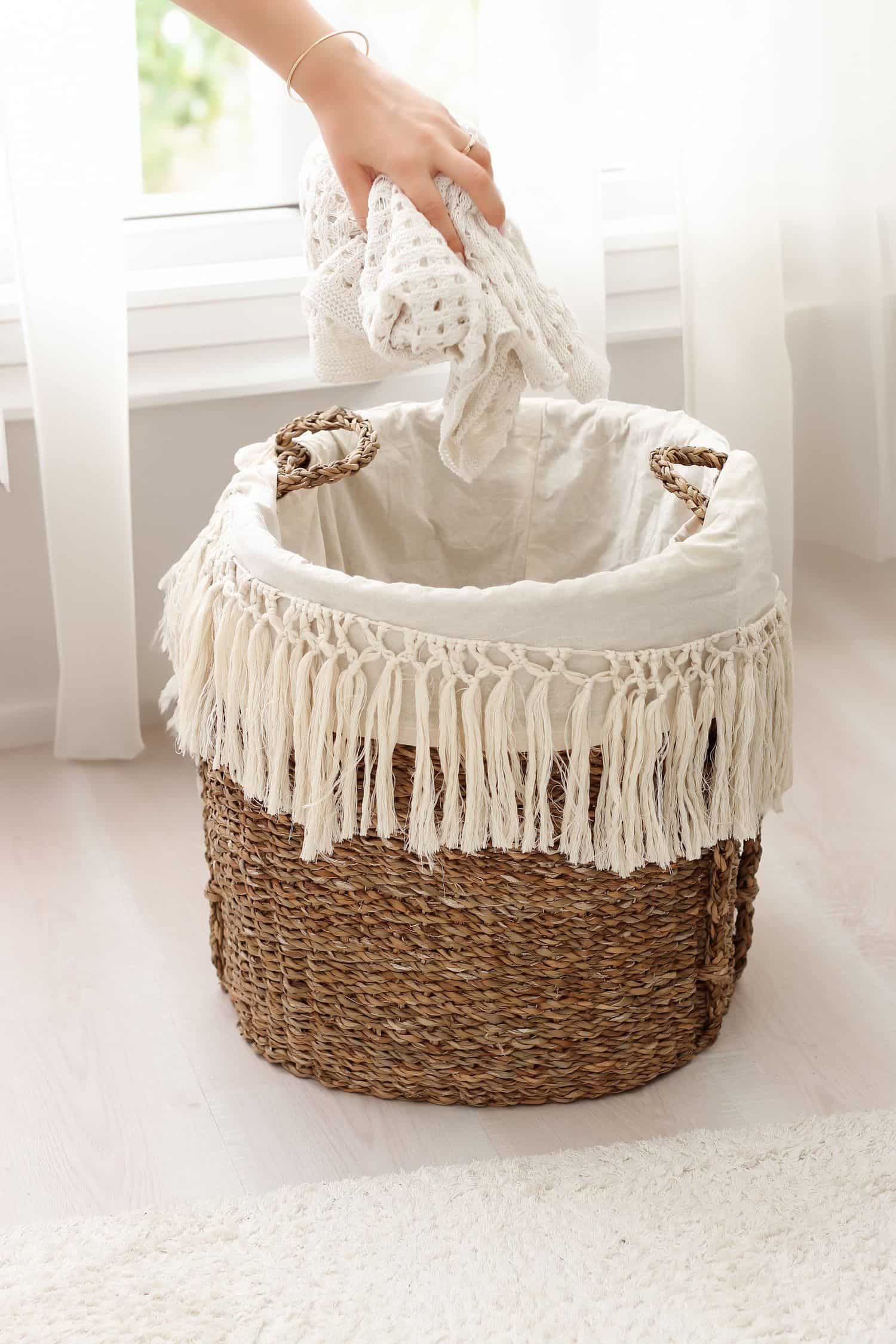 A basket of freshly folded laundry by a sunlit window